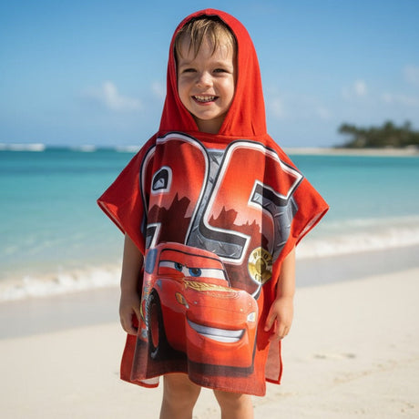 Child wearing a red superhero cape on a beach