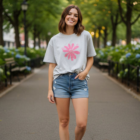 Gray t-shirt with a pink flower design on a dark surface
