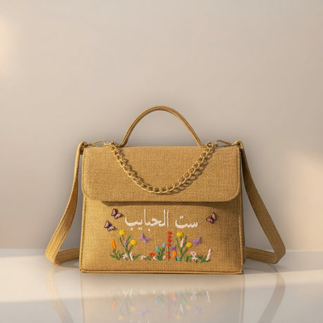 Woven handbag with floral embroidery and text on a neutral background