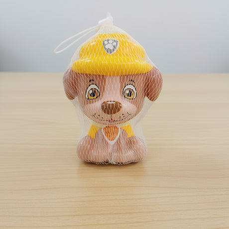 Small plush toy with a yellow hat in a clear bag on a wooden surface