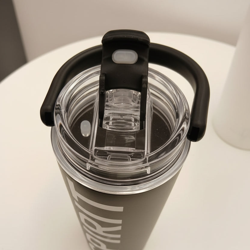 Clear water bottle with black lid and handle on a white surface