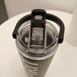 Clear water bottle with black lid and handle on a white surface