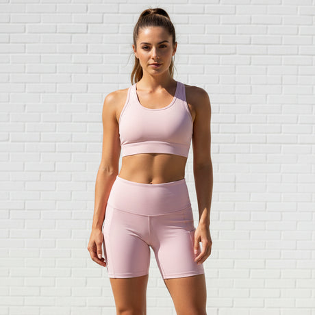 Woman wearing a pink athletic outfit against a white brick wall