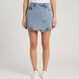 Blue denim shorts on a table with a mirror reflecting clothing in the background