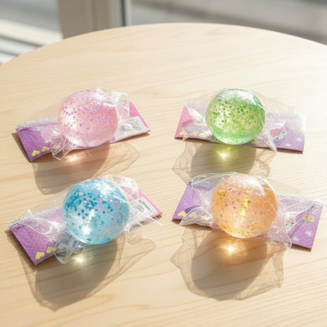 Four colorful squish balls in clear plastic bags on a wooden surface.