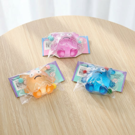 Three colorful plush toys in clear packages on a wooden surface.