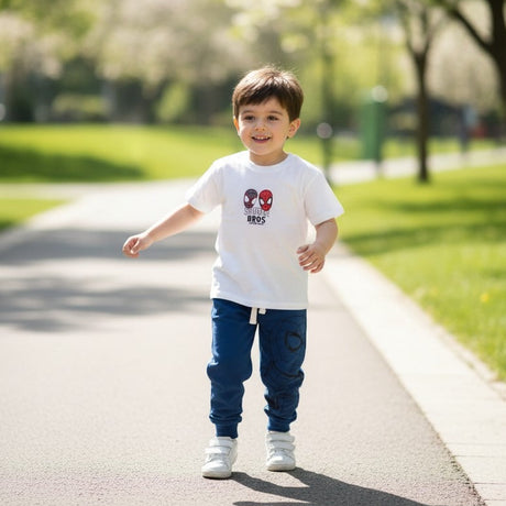 Child wearing a white t-shirt with a graphic design, standing on a path in a park.