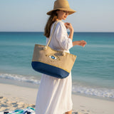 Woman on a beach holding a tote bag with an eye design