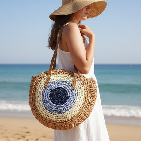 Woman on a beach holding a round, woven bag with a blue center.