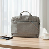Gray laptop bag on a wooden table with a smartphone, notebook, and cup in a home office setting.