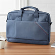 Blue laptop bag on a desk with a laptop, coffee cup, and plant.