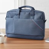 Blue laptop bag on a desk with a laptop, coffee cup, and plant.