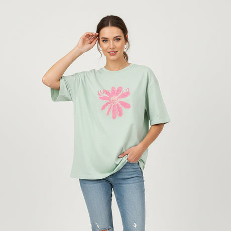 Light green t-shirt with a pink floral design on a dark surface