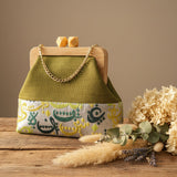 Green handbag with floral pattern on a glass surface, with a store interior in the background.