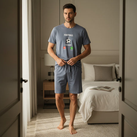 Man wearing a blue t-shirt and shorts standing in a bedroom.