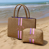 Two brown bags with pink and purple stripes on a sandy beach.