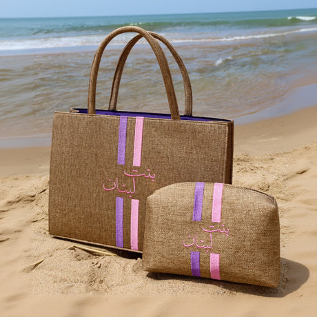 Two brown bags with pink and purple stripes on a sandy beach.