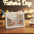 A mug with 'Best Dad' and 'Best DAD' text in a gift box, with 'Happy Father's Day' sign and blurred lights in the background.