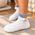 White fuzzy kids socks with a blue cuff and a plush animal face with orange pom nose
