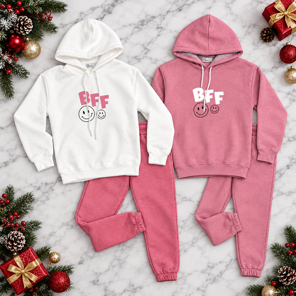White and pink BFF jogging sets laid out side by side with festive greenery