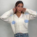 Close view of a white cloud cardigan with soft blue 3D cloud details