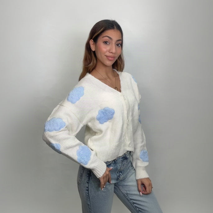 White knit cardigan with fluffy blue cloud appliques, seen at an angle