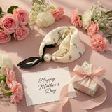 Cream-colored foulard with black ribbon and pearl on a marble surface