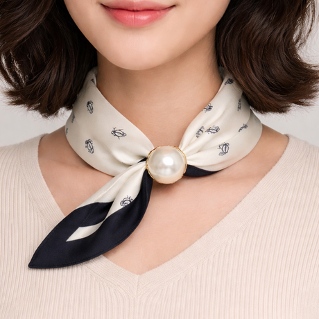 Woman wearing a white foulard with a pearl knot against a neutral background