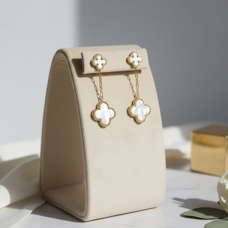 Gold and white clover-shaped earrings on a stand