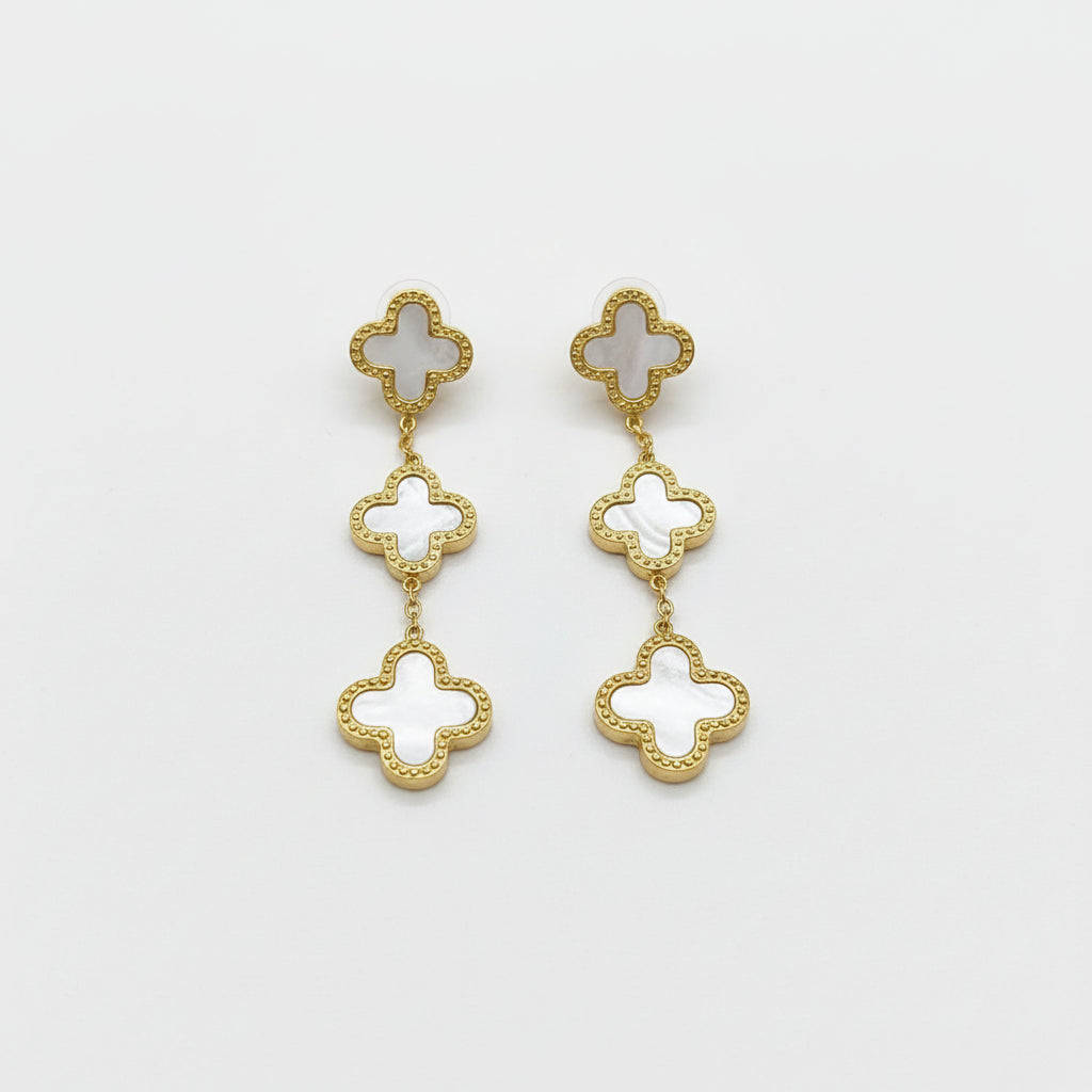 Gold and white clover-shaped earrings on a background
