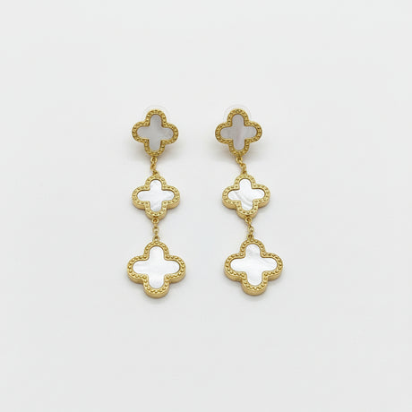 Gold and white clover-shaped earrings on a background
