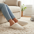 Cream boucle mules worn seated on a sofa, low domed vamp and a completely open heel