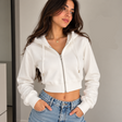 Woman in a white cropped zip hoodie with a drawstring hood and light blue jeans
