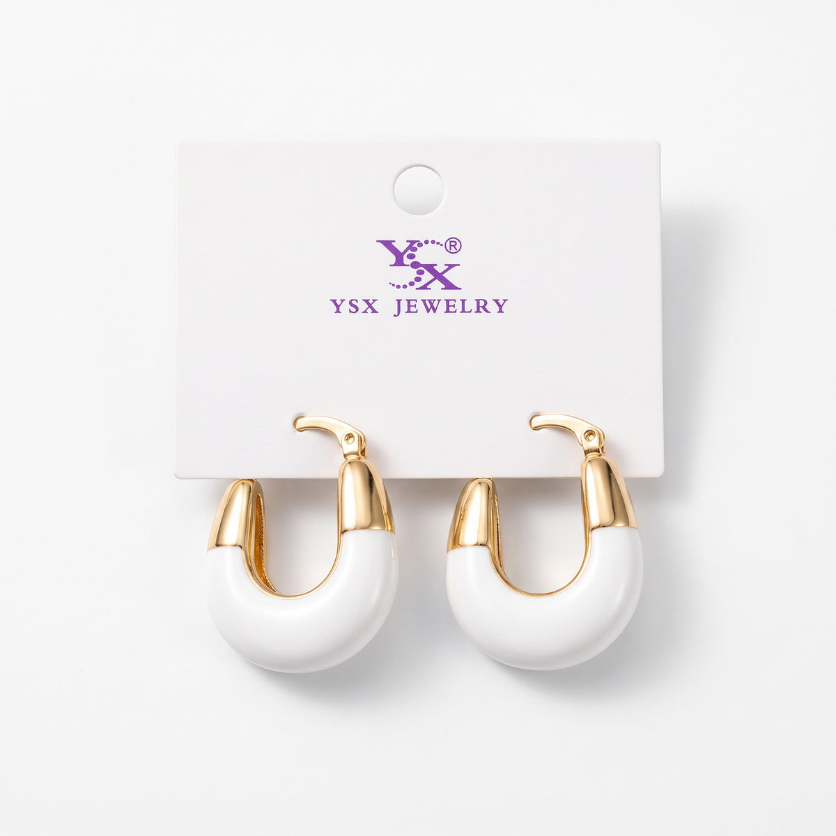 Chunky white enamel hoop earrings with polished gold tone tops on a card