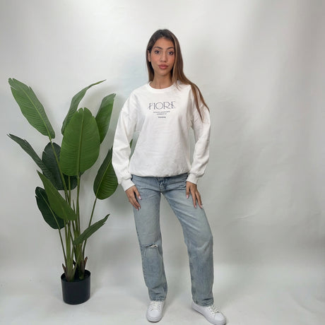 Full length view of a white Fiore script sweatshirt styled with straight leg jeans and sneakers