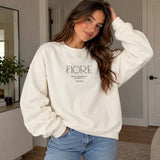 Woman in a white crew neck sweatshirt with minimalist Fiore lettering, worn with light jeans