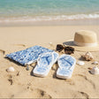 Flip-flops with blue floral pattern on sand by the ocean