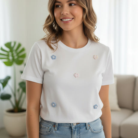 Woman wearing a white tshirt with floral embellishments in a living room setting