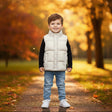 Boy in a white sleeveless puffer vest over a black long sleeve top with light blue jeans