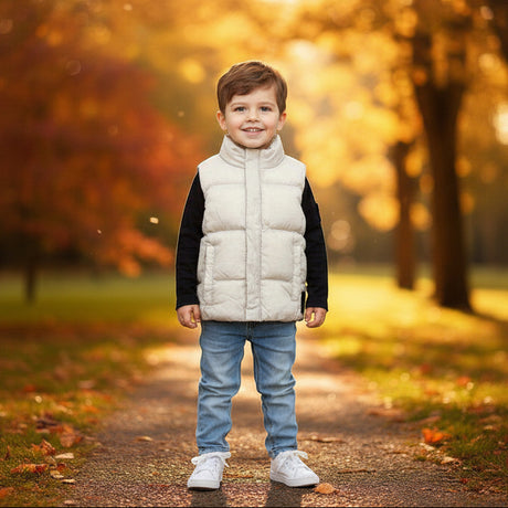 Boy in a white sleeveless puffer vest over a black long sleeve top with light blue jeans
