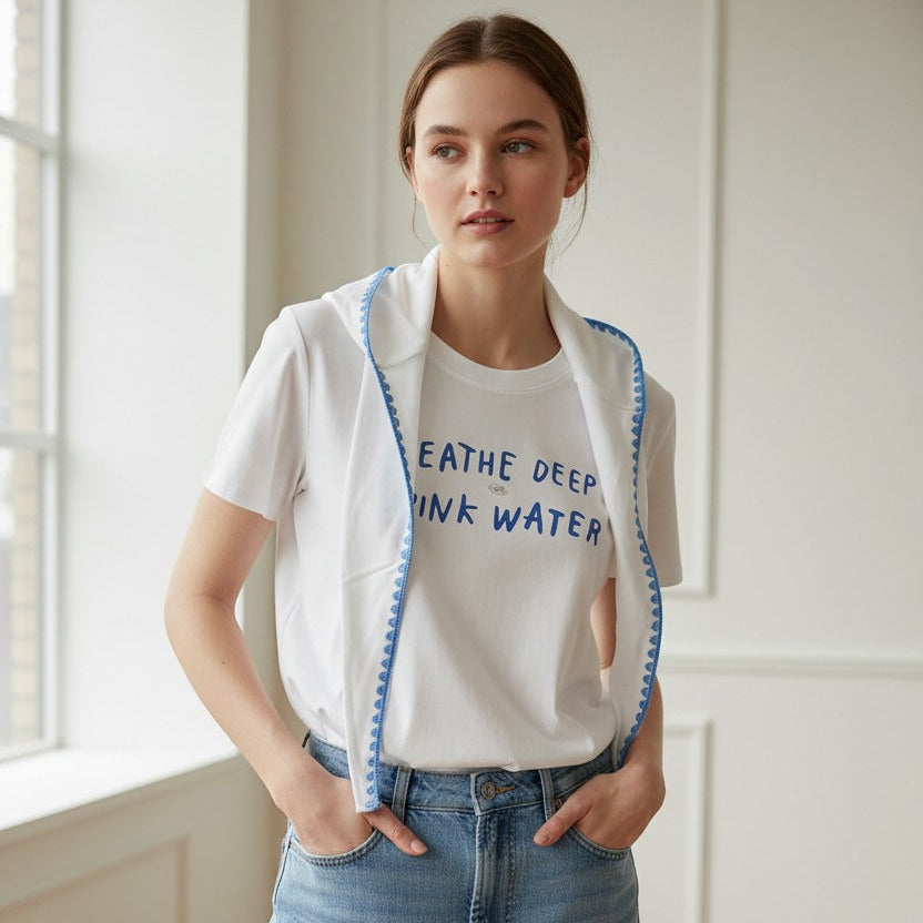Woman wearing a white hydration tshirt with text and a white cardigan in a bright room