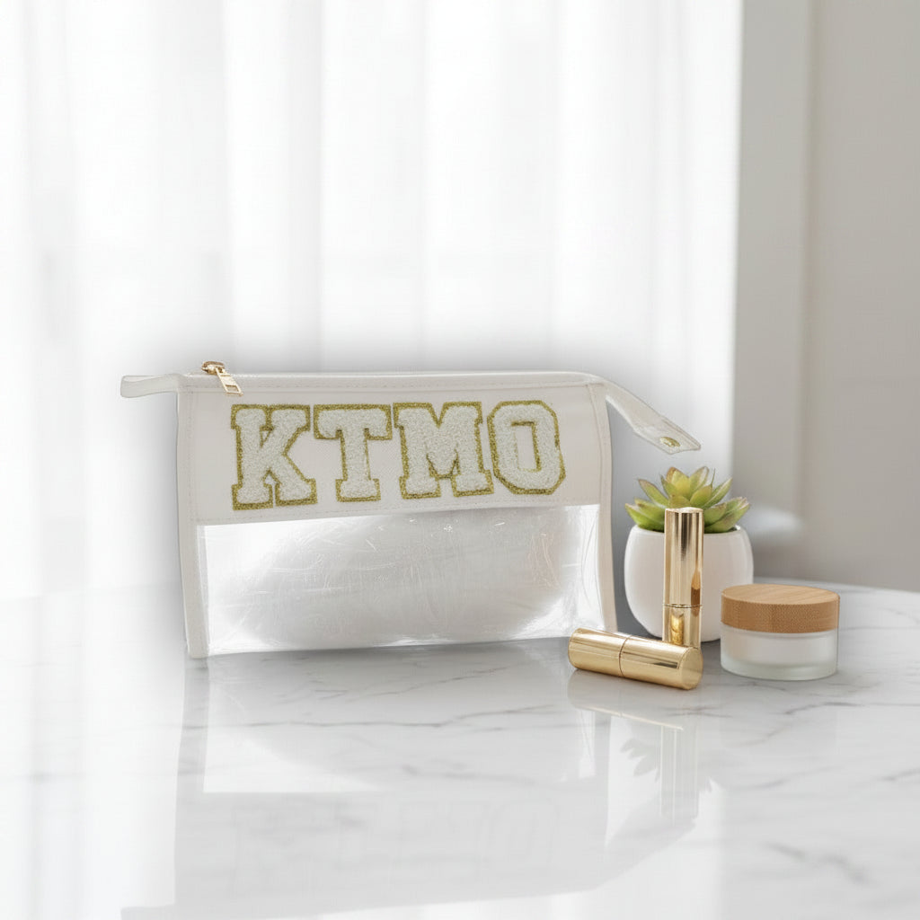 White pouch with 'KTMO' branding on a marble surface with cosmetic items