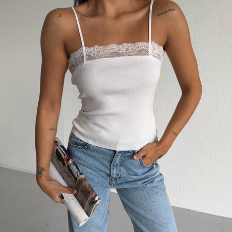 Person wearing a white lace-trimmed top and blue jeans, holding a magazine