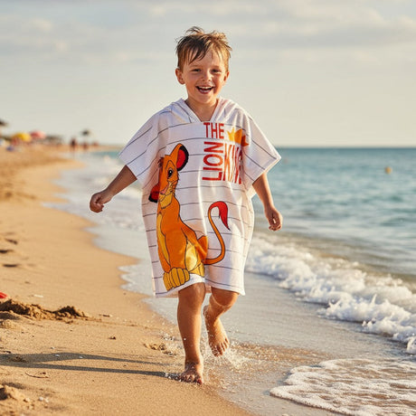 Boy running on the beach in a white Lion King hooded poncho towel with grey pinstripes