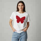 Woman wearing a white tshirt with a red butterfly design on a plain background