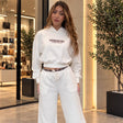 Woman in a white cropped slogan hoodie and wide leg pants with a plaid waistband, front view