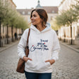 White slogan hoodie styled with jeans and a tote bag on a cobbled square