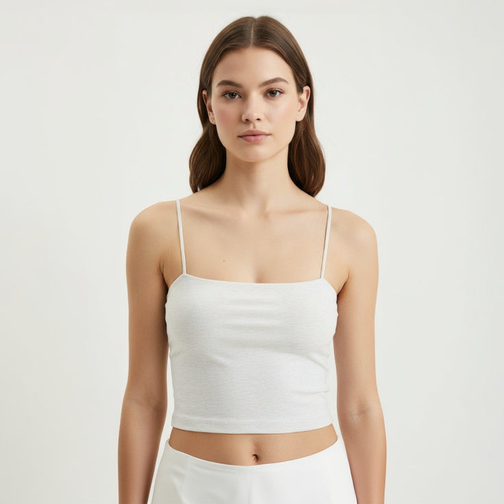 Woman wearing a white tank top against a plain background