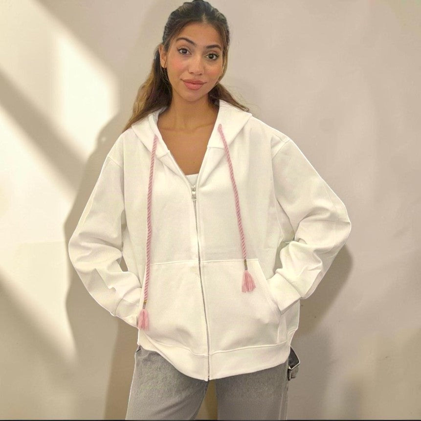 White hoodie jacket worn zipped with hands tucked into the front pockets
