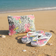 White tropical pouch and flip flops on a sandy beach 
